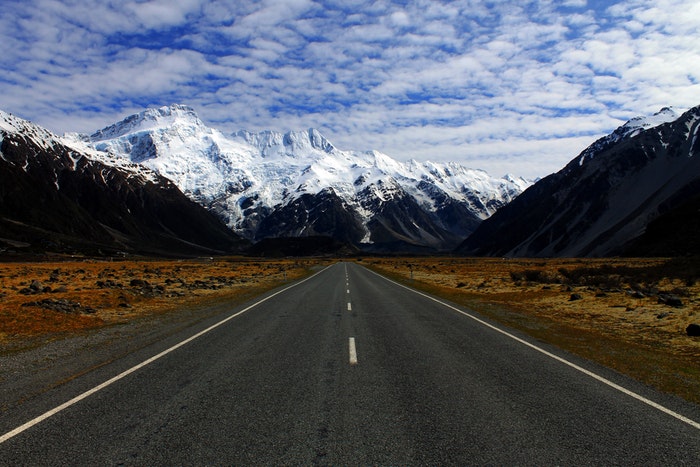 Road leading the eyes to snowy mountains through utilising leading line composition 