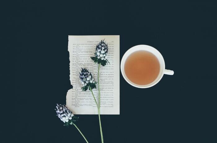 Photo of a piece of paper with a flower and a cup of tea next to it